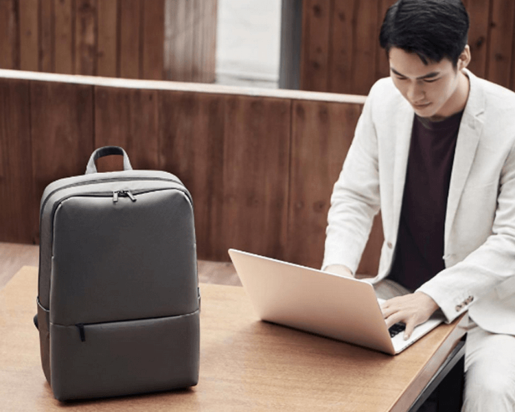 Парень работает за ноутбуком, рядом стоит рюкзак Mi Classic Business Backpack 2